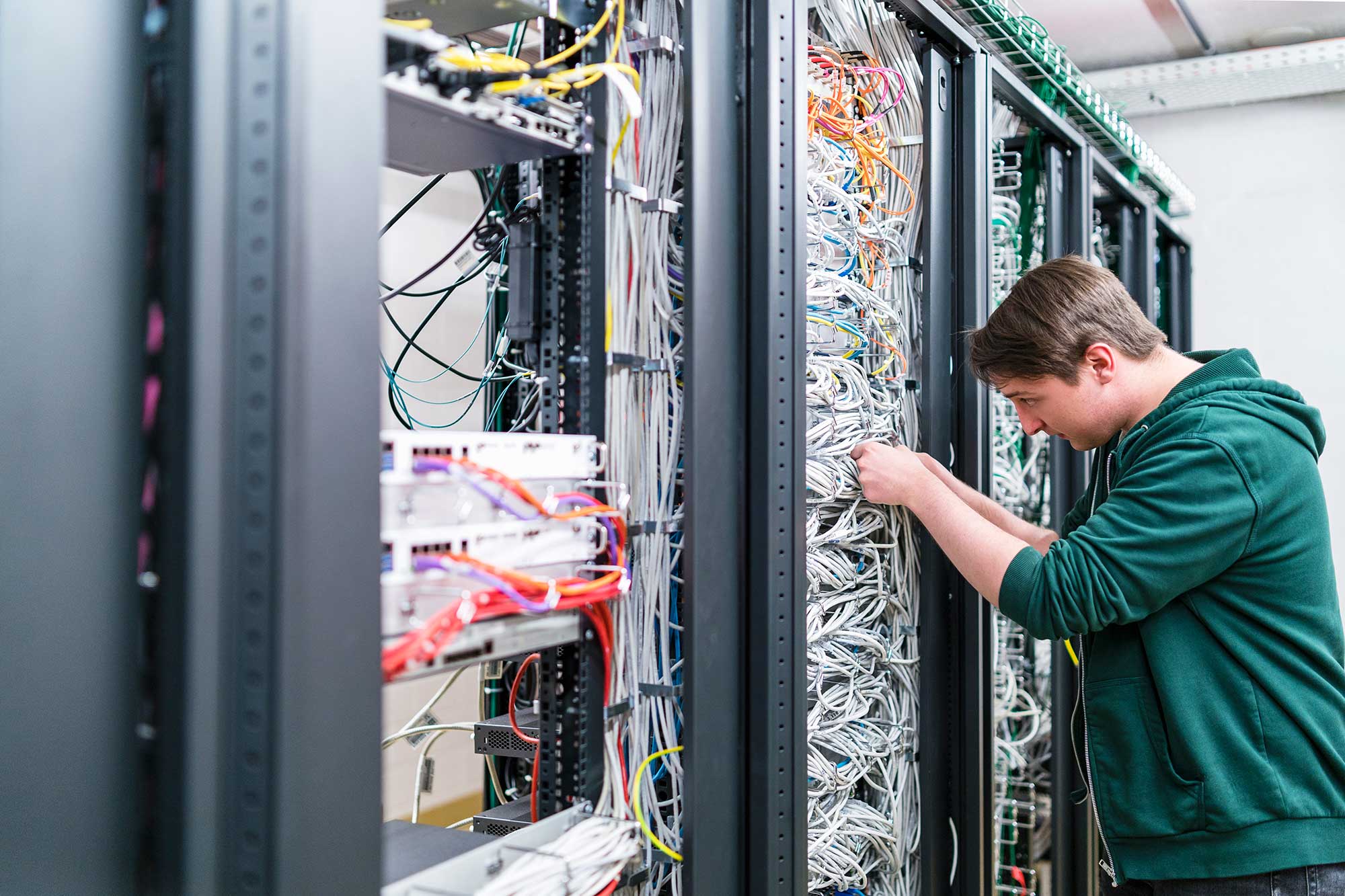 teenager-working-with-cables-in-server-room-2022-12-16-22-21-27-utc